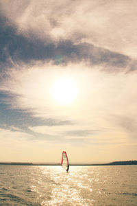 Person in sea against sky during sunset