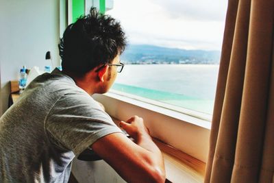 Man looking at sea seen through window