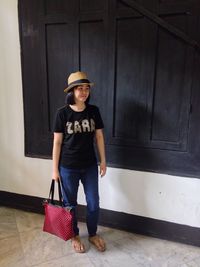 Full length of young woman standing against wall
