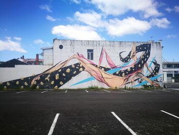 Graffiti on wall by road against sky in city