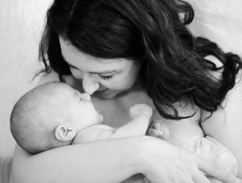 Close-up of mother with baby sleeping on bed