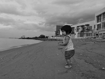 Boy standing on beach against sky