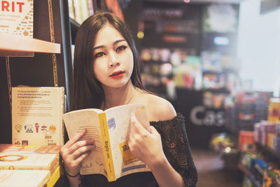 Portrait of young woman reading book