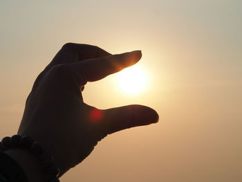 Midsection of person against sun during sunset