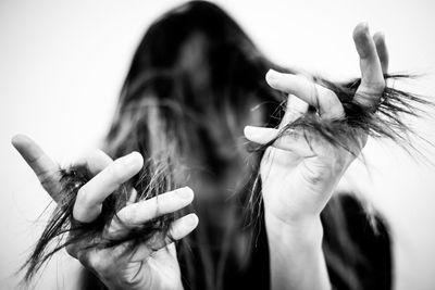 Low angle view of young woman with hand in hair against white background