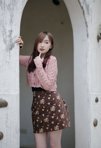 Young woman standing against wall