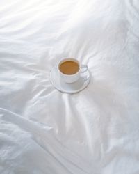 High angle view of coffee cup on bed