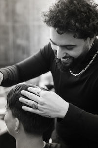 Barber cutting hair of man at salon