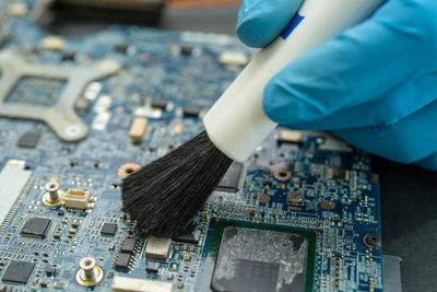 Technician use brush and air blower ball to clean dust in circuit board computer.  