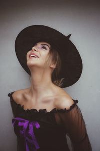 Young woman wearing witch hat against gray background