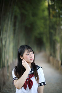 Young woman looking away while standing amidst bamboo groove