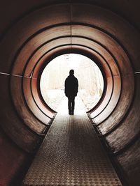 Rear view of person standing in tunnel