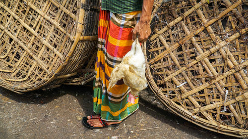 Low section of man holding chicken in market