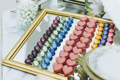 High angle view of macaroons and candies on mirror