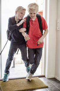 Boys pushing each other while entering home from school