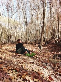 Side view of woman sitting in forest