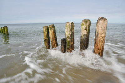 Panoramic shot of wooden posts in sea against sky