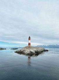 Lighthouse by sea against sky