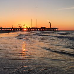 Pier over sea against sky at sunset