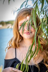 Portrait of smiling teenage girl standing by leaves