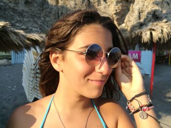 Close-up of thoughtful girl wearing sunglasses while standing at beach