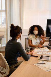 Businesswomen wearing mask having discussion at office