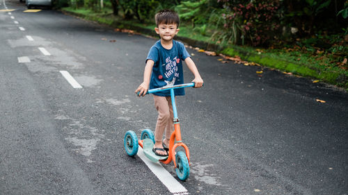 Boy riding push scooter on road in city