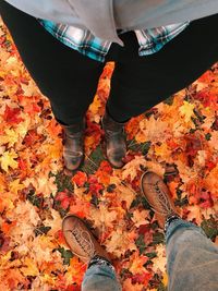 Low section of people standing on autumn leaves