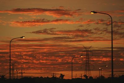 Low angle view of silhouette electricity pylon against sky during sunset