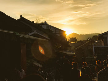 Crowd in city against sky during sunset