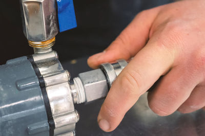 Cropped hand of plumber attaching pipe on metal