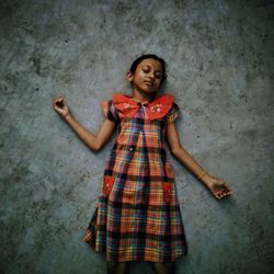 Portrait of a smiling young woman standing against wall