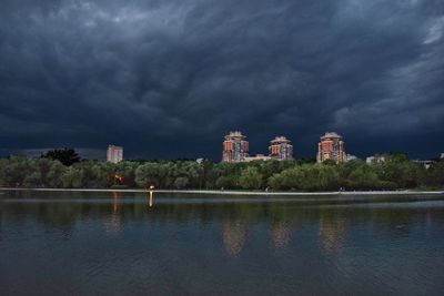 Reflection of buildings in lake against cloudy sky