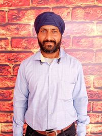 Portrait of man standing against brick wall