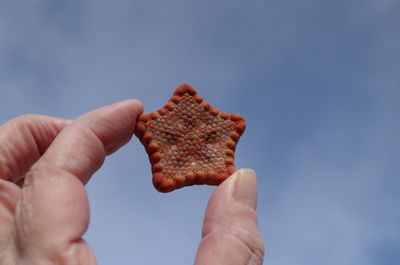 Close-up of hand holding ice cream against sky