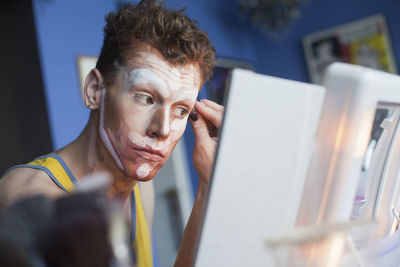 Young man applying drag makeup