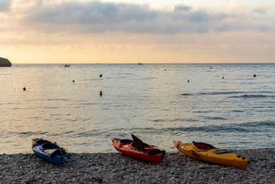 Pebble beach with empty kayaks at sunrise.