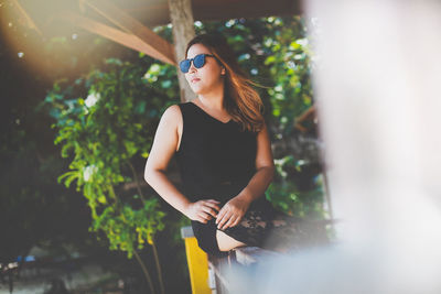 Woman looking away while sitting on railing 