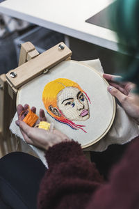 Hands of young woman choosing threads for embroidery in studio