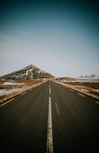 Empty road amidst landscape against sky