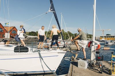 Active senior couples boarding boat at harbor during sunny day