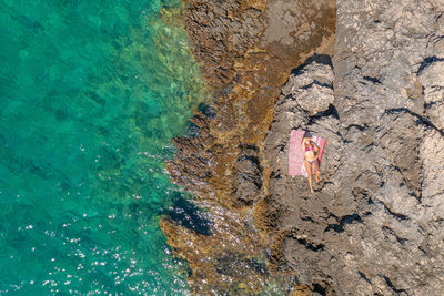 Aerial view of a girl sunbathing on the rocky beach, paklinski otoci islands in hvar, adriatic sea