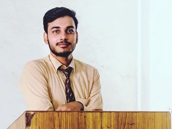 Portrait of young man standing against wall