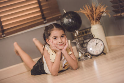 Full length portrait of cute smiling girl lying on floor at home