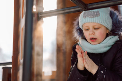 Little girl warms her frozen ankles on a walk on a frosty winter day