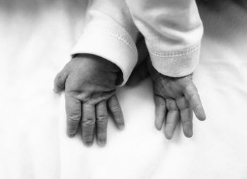 Cropped hands of baby on bed