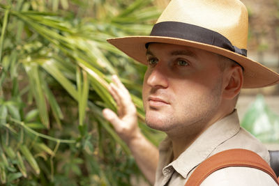 Middle-aged man wearing sunhat among green wild leaves.travel,tourism, beauty concept.close-up