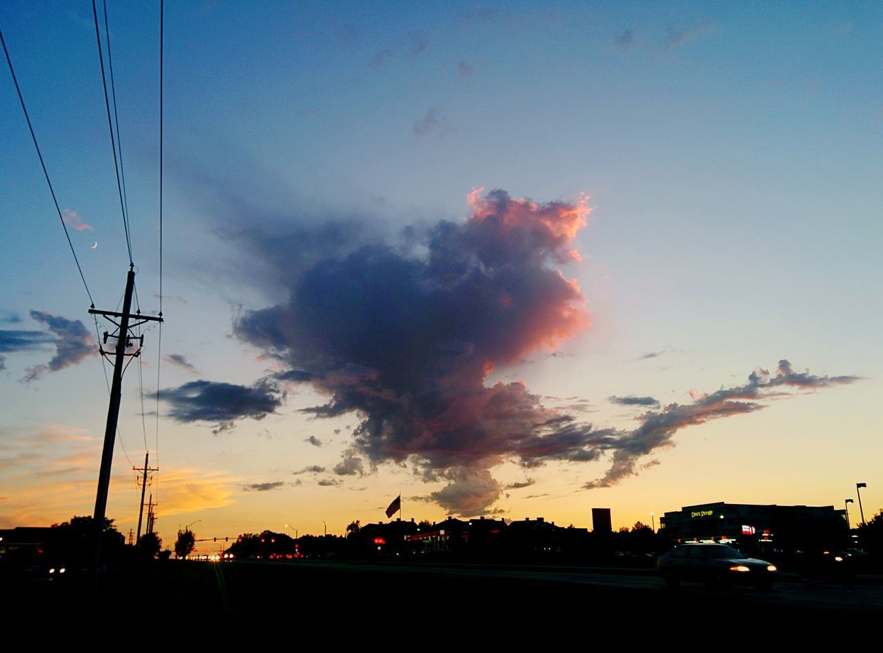 sunset, land vehicle, sky, mode of transport, road, power line, street light, cloud - sky, outdoors, city, orange color, cable, no people, cloud, power supply, nature, illuminated, city street, dramatic sky, cloudy, city life, beauty in nature, scenics