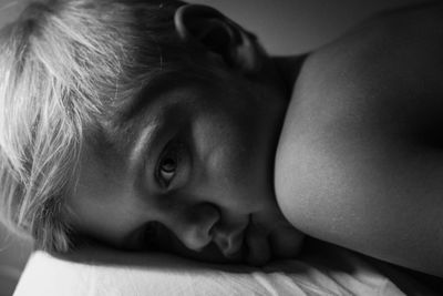 Close-up of thoughtful innocent boy relaxing on bed