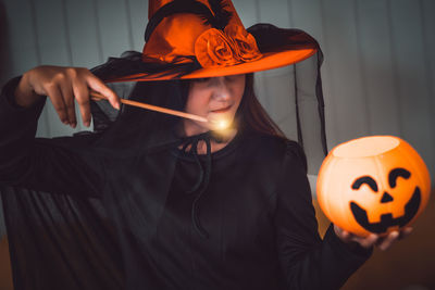 Midsection of woman holding illuminated pumpkin during halloween